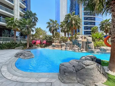 a large swimming pool with rocks in a city at TRPS - Paramount Tower D, Business Bay - Premium 1BR Furnished, High Floor, Ready Move In in Dubai