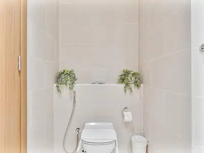 a white bathroom with a toilet with two plants on it at Savis Homes - Canal Front Residence Near Al Wasl Safa Park with Skyline View in Dubai