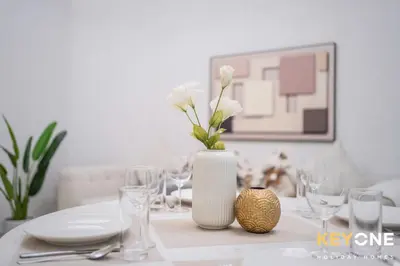 a table with a white vase with white flowers in it at Magnificent Two Bedroom Beachfront in Dubai