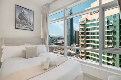 a white bed in a room with a large window at Luxe 2 Bed with Burj View, 5 Min Walk to Dubai Mall, PS5 by Vista Stays Dubai Downtown in Dubai