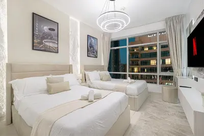 a white bedroom with two beds and a tv at Luxe 2 Bed with Burj View, 5 Min Walk to Dubai Mall, PS5 by Vista Stays Dubai Downtown in Dubai