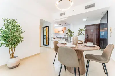 a dining room with a wooden table and chairs at Easy Metro and Tram Access 1BR, Offering Partial Canal, SZR, and City Views, Just Minutes from Marina Mall, Marina Diamond 6, Dubai Marina by Deluxe Holiday Homes in Dubai