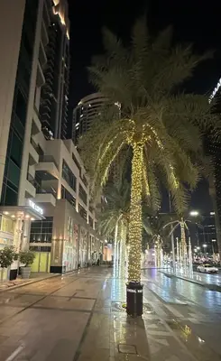 a palm tree with lights on a street at night at Downtown Dubai Beautiful Upgraded 1-bedroom apartment in Dubai