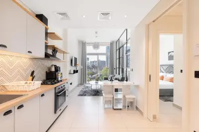 a kitchen with white cabinets and a dining room with a bed at StayShort - Dubai Hills sleeps 4 in a Great Location in Dubai