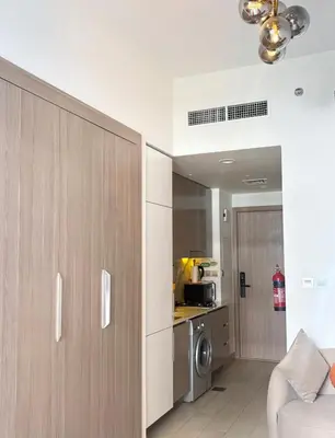 a living room with a kitchen with a microwave at Cozy Studio 15 Min From Burj Khalifa in Dubai