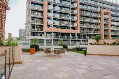 an outdoor patio with a table and chairs in front of a building at Bright Studio in Azizi Riviera with Patio & Pool in Dubai