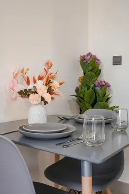 a table with plates and vases of flowers on it at Bright Studio in Azizi Riviera with Patio & Pool in Dubai