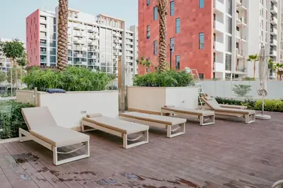 a group of benches on a patio with buildings at Bright Studio in Azizi Riviera with Patio & Pool in Dubai