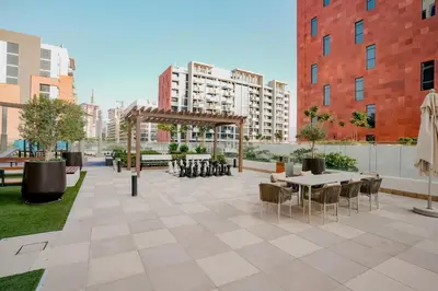 an outdoor patio with tables and chairs and buildings at Bright Studio in Azizi Riviera with Patio & Pool in Dubai