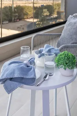a white table with a blue napkin and glasses on it at Frank Porter - Binghatti Corner in Dubai