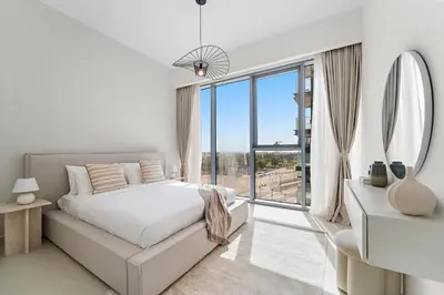 a white bedroom with a bed and a large window at Partial Canal View 2BR plus Maid close to Safa Park in Dubai