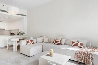a white living room with a white couch and a table at Partial Canal View 2BR plus Maid close to Safa Park in Dubai