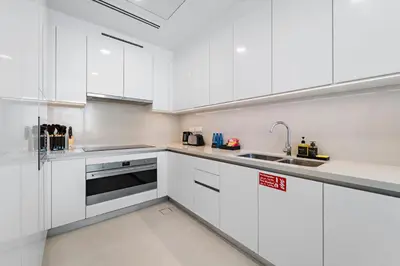 a white kitchen with white cabinets and a sink at Partial Canal View 2BR plus Maid close to Safa Park in Dubai