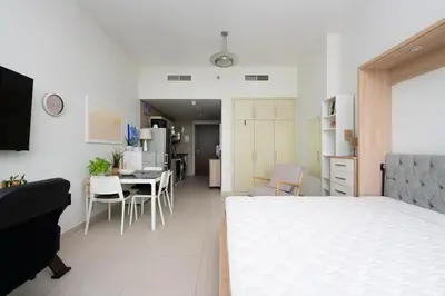 a bedroom with a white bed and a dining room at Fully Furnished Studio Hilliana Tower Sea View and Burj View in Dubai