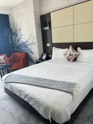 a bedroom with a large bed and a chair at Movenpick Apartment JLT in Dubai