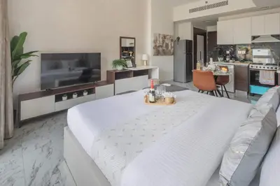 a living room with a white table and a kitchen at Frank Porter - Jwelz Residence in Dubai