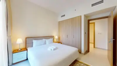 a bedroom with a large white bed and a doorway at Vacationer l Chic 2 Bedroom l Prime Location in Creek Harbour l Pool View in Dubai