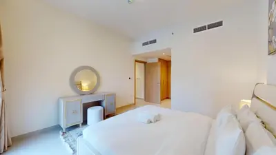 a white bedroom with a white couch and a mirror at Vacationer l Chic 2 Bedroom l Prime Location in Creek Harbour l Pool View in Dubai