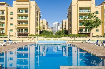 a swimming pool with chairs and some buildings at Vacationer l Modern 1 Bedroom l Aesthetic Interior l Free Wi-Fi in Dubai