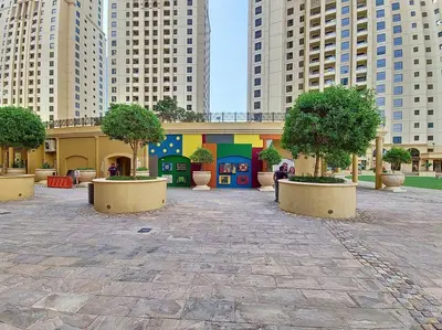 a courtyard with trees and a building with tall buildings at Vacationer I Upgraded , Luxury 2 Bedroom Apartment Near JBR Beach, Prime Spot in Dubai