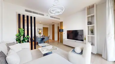 a living room with a white couch and a tv at Palace Residences - Two Bedroom with Creek View in Dubai