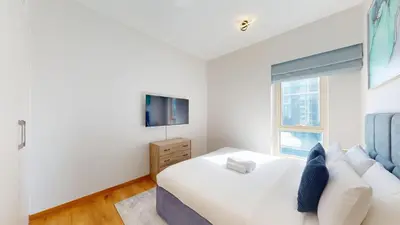 a white bedroom with a large bed and a window at Vacationer l Glamorous 2 Bedroom l Stunning Lake View l Free Wi-Fi in Dubai