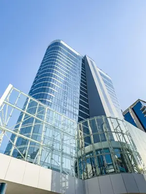 a tall glass building in front of a blue sky at Deluxe 1BR Business Bay - with Canal and Skyline Views in Dubai
