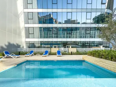 a swimming pool with chairs and a building at Deluxe 1BR Business Bay - with Canal and Skyline Views in Dubai