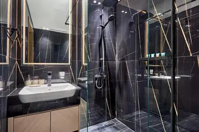 a black tiled bathroom with a sink and a shower at Modern 1BR Urban Escape at Blue Paradise in Dubai