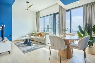 a living room with a couch and a table and chairs at Modern 1BR Urban Escape at Blue Paradise in Dubai