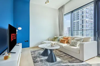 a living room with a white couch and a large window at Modern 1BR Urban Escape at Blue Paradise in Dubai