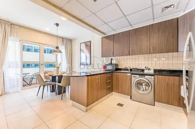 a kitchen with a washing machine and a table at Sky-Level 2BR with Partial Marina View, Just Steps to Dubai Tram and Minutes from the Beach, Elite Residence, Dubai Marina by Deluxe Holiday Homes in Dubai