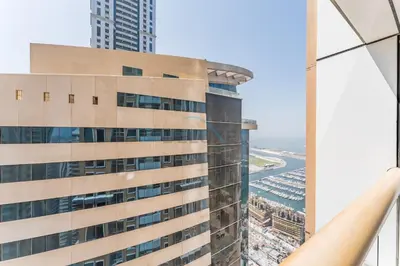 a view of a tall building with the ocean in the background at Sky-Level 2BR with Partial Marina View, Just Steps to Dubai Tram and Minutes from the Beach, Elite Residence, Dubai Marina by Deluxe Holiday Homes in Dubai