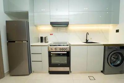 a white kitchen with a stove and a washer at AWS Holiday Homes - Iconic Burj Khalifa Views in Dubai