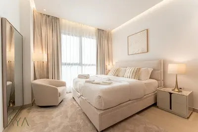 a white bedroom with a large bed and a chair at Chic 1BR Apartment near Madinat Jumeirah BurjAlArab in Dubai