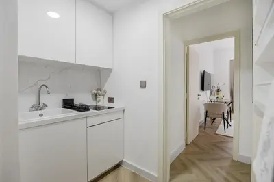 a white kitchen with a sink and a table at Spacious and luxurious studio with amazing marina view!Rimal ! in Dubai