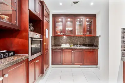 a kitchen with wooden cabinets and a white tile floor at 2BHK Downtown Breathtaking Burj Khalifa View in Dubai