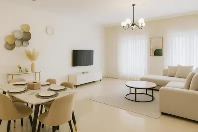 a white living room with a table and a couch at The Rosewood HH at Sarai Residence, Palm Jumeirah, 5 mins from the Iconic Atlantis The Royale in Dubai
