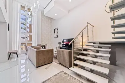 a staircase in a living room with white walls at Duplex 2BR next to Marina Beach in Dubai