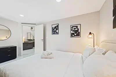 a white bedroom with a large bed and a bathroom at Duplex 2BR next to Marina Beach in Dubai