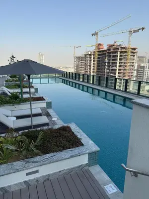 a swimming pool with an umbrella and some buildings at Elegant 1-Bedroom The Crest, Near Downtown Dubai in Dubai