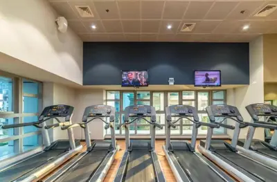 a fitness room with cardio equipment and televisions at FIRST CLASS 2BR Luxury Marina Bliss in Dubai