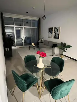 a living room with green chairs and a glass table at Specious 1 bd close to Sea Jumeirah in Dubai