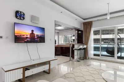 a living room with a tv on the wall at Cozy 1BR with gym & pool in heart of Marina - Opal Tower in Dubai