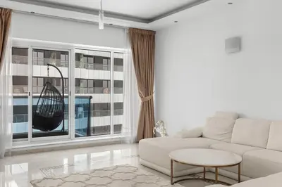 a living room with a white couch and a large window at Cozy 1BR with gym & pool in heart of Marina - Opal Tower in Dubai