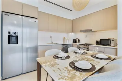 a kitchen with a table with chairs and a refrigerator at 2Bed with spectacular Burj Khalifa & fountain view in Dubai