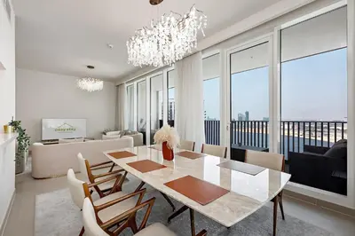 a dining room with a table and chairs and a couch at Commodious 3BR Apartment Canal View Creek Harbor in Dubai