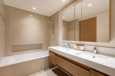 a bathroom with a sink and a tub and a mirror at Commodious 3BR Apartment Canal View Creek Harbor in Dubai