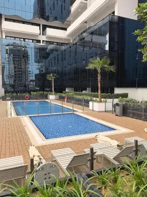 a swimming pool in front of a building at 10 min to Burj Khalifa 1BR in Hotel-style building Luxury Stay in Dubai