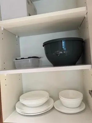 a group of plates and bowls on a shelf at 10 min to Burj Khalifa 1BR in Hotel-style building Luxury Stay in Dubai